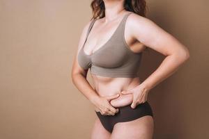 selbstliebende junge Frau plus Größe in Unterwäsche auf beigem Hintergrund, Körperliebe foto
