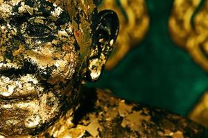 Nahaufnahme des betenden buddhistischen Mönchs, der mit goldener Farbe bedeckt ist. foto