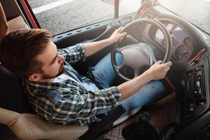 männlicher lkw-fahrer, der sein großes fahrzeug fährt foto