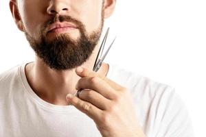 Mann, der seinen Bart mit einer Schere trimmt foto