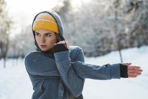 junge sportliche Frau, die sich vor ihrem Wintertraining aufwärmt foto