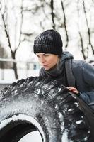 Sportliche Frau, die während ihres Trainings an verschneiten und kalten Wintertagen mit einem Reifen trainiert foto
