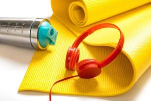 Proteinshaker, gelbe Fitnessmatte und rote Kopfhörer. foto