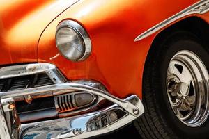 glänzendes orangefarbenes Oldtimerauto, das auf der Straße geparkt ist foto