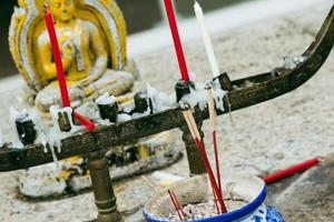 Nahaufnahme des buddhistischen Altars, der Kerzen und der betenden Buddha-Statue. foto