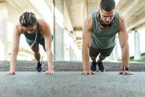 sportliches paar und fitnesstraining im freien. Mann und Frau machen Liegestütze. foto