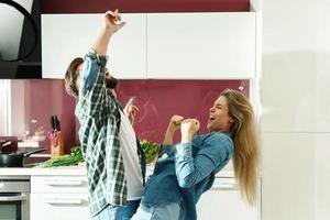 Paar tanzt in der Küche beim Kochen am sonnigen Morgen foto