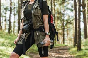 Wanderin mit moderner spiegelloser Kamera im grünen Wald foto