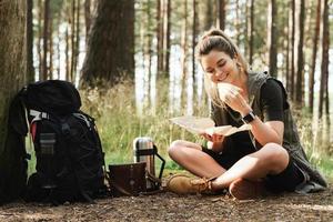 weibliche wanderer während des kleinen halts, der sandwich im grünen wald isst foto