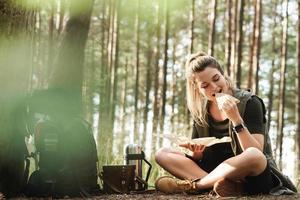 weibliche wanderer während des kleinen halts, der sandwich im grünen wald isst foto