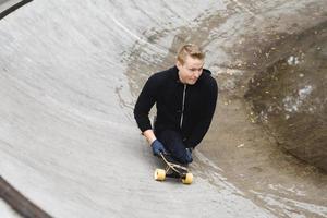 junger behinderter kerl mit einem longboard in einem skatepark foto