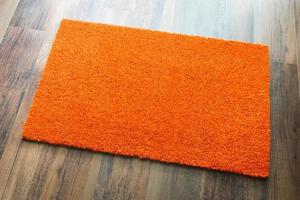 leere orange Willkommensmatte auf Holzbodenhintergrund bereit für Ihren eigenen Text foto