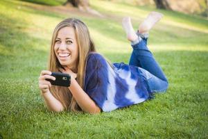 lächelnde junge Frau mit Handy im Freien foto