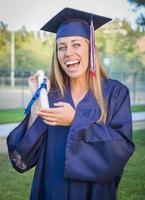 Ausdrucksstarke junge Frau mit Diplom in Mütze und Kleid foto