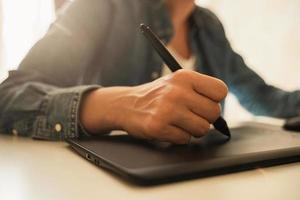 weibliche hand mit stiftähnlichem stift und grafiktablett foto