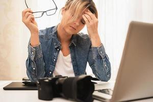 fotografin, die zu hause an ihrem arbeitsplatz unter kopfschmerzen leidet foto