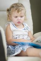 blondes blauäugiges kleines Mädchen, das ihr Buch liest foto