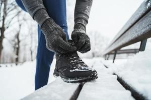 Jogger, der seine Schuhe während seines Wintertrainings schnürt foto