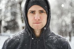 Schöner sportlicher Mann mit Hoodie während seines Wintertrainings foto