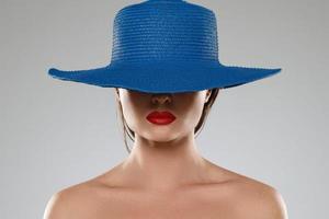 Porträt eines fremden Mädchens mit roten Lippen und blauem Hut foto
