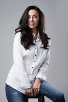 Schönes Model mittleren Alters mit weißem Hemd und Jeans in einem Fotostudio foto