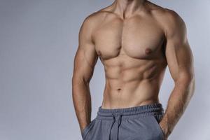 muskulöser männlicher Torso vor grauem Hintergrund foto