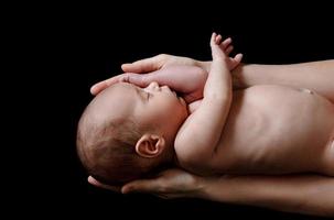 süßes neugeborenes baby, das in den händen der mutter liegt foto