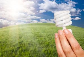 weibliche hand mit energiesparlampe über feld foto