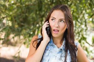 unglückliche junge Frau gemischter Abstammung, die draußen am Handy spricht foto