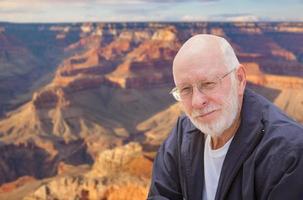 glücklicher älterer Mann, der am Rand des Grand Canyon posiert foto