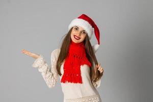 Mädchen in Weihnachtsmütze und rotem Schal foto