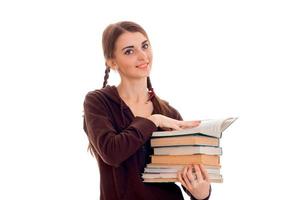 Fröhliche junge Studentin mit Büchern in brauner Sportkleidung, die in die Kamera schaut und isoliert auf weißem Hintergrund lächelt. Konzept der Studentenjahre. Studienkonzept. foto