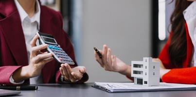 Diskussion mit einem Immobilienmakler, Hausmodell mit Makler und Kunde, der für den Kaufvertrag, den Abschluss einer Versicherung oder das Darlehen von Immobilien oder Grundstücken bespricht. foto