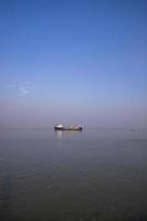 Landschaftsansicht eines kleinen Frachtschiffs vor blauem Himmel auf dem Fluss Padma in Bangladesch foto
