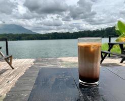 ein glas eiskaffee mit seeblick im hintergrund foto