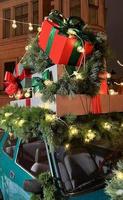 Santas alter Oldtimer mit Geschenkboxen an der Spitze. nahaufnahmezweige von nadelbäumen, die mit einer glänzenden lichtgirlande verziert sind. perfekter festlicher inhalt für geschichtenhintergrund, vertikales banner. foto