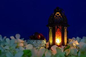 Laterne auf blauem Hintergrund mit Dattelfrüchten auf Orchideenblüte für das muslimische Fest des heiligen Monats Ramadan Kareem. foto