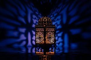 schwarze laterne mit reflexion vom blauen hintergrund für das muslimische fest des heiligen monats ramadan kareem. foto