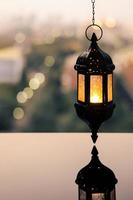 hängende laterne mit abendhimmel und stadt-bokeh-lichthintergrund für das muslimische fest des heiligen monats ramadan kareem. foto