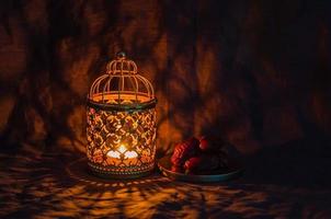 goldene laterne und dattelfrüchte auf dunklem hintergrund für das muslimische fest des heiligen monats ramadan kareem. foto