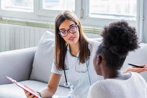 ärztin, die im büro arbeitet und dem patienten zuhört, sie erklärt ihre symptome, gesundheitsversorgung und hilfekonzept seriöser arzt mit zwischenablage und patient im krankenhaus. foto