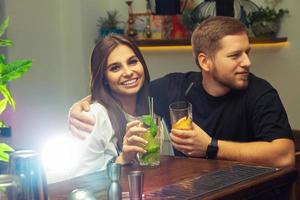 Paar sitzt mit Cocktails an der Bar foto