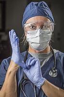 betroffene Ärztin oder Krankenschwester, die Gesichtsschutzkleidung anzieht foto