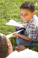 Vater und Sohn gemischter Rassen spielen mit Papierflugzeugen foto