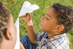 Vater und Sohn gemischter Rassen spielen mit Papierflugzeugen foto