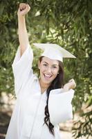 glückliches graduierendes Mischlingsmädchen in Mütze und Kleid foto