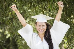 glückliches graduierendes Mischlingsmädchen in Mütze und Kleid foto