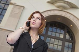 Junge Geschäftsfrau am Handy vor dem Rathaus foto