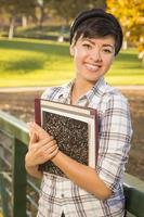 Porträt einer hübschen gemischtrassigen Studentin, die Bücher hält foto