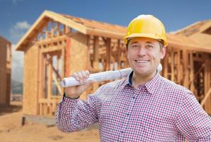 auftragnehmer mit helm, der baupläne auf der baustelle zu hause hält foto